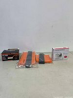 Photo showing the boxed 45 mini LED lights, the solar charge controller box, and packaged orange and black measuring tools against a white wall.