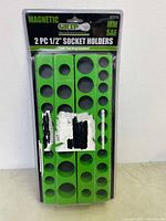 Front view of original packaging showing two green magnetic 1/2 inch socket holders inside blister pack with label Grip 67215 and MM SAE indicated.