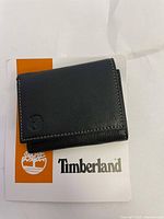 Closed view of black Timberland wallet on Timberland branded card insert showing wallet texture and logo embossing