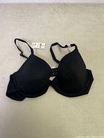 Front view of black padded bra with molded cups and adjustable straps, showing tag attached.