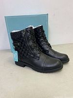 Side angled view of the black Vepose ankle boots showing quilting on heel, side zipper, knit cuff, and laces