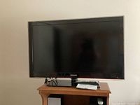 Samsung 40-inch LCD TV displayed on stand with remote and manual placed on top, front view.