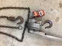 Come along winch with chain and large metal hooks, A&W soda can for size reference.