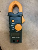 Greenlee CM-600 handheld clamp meter close-up showing rotary dial and HOLD button