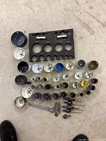 Top-down photo of hole saws, mandrels, and caliper arranged on concrete floor.