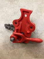 Top and side view of red pipe vice showing lever, chain clamp, and mounting holes.