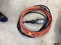 Overall view of the coiled trouble light and extension cord on a concrete floor.