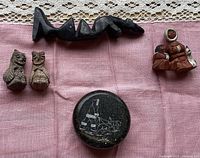 Photo showing all four items: soapstone figure with two figures stacked, soapstone circular box, pair of pottery man and woman figures, and pair of pottery bird figures + signed details.