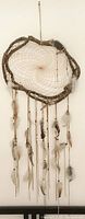 Full view of the large dreamcatcher showing its wooden frame, central woven web, and hanging leather strands with feathers.