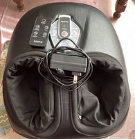 Top view of RENPHO foot massager showing remote control and power adapter placed on top of device with fabric foot slots.