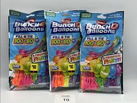 Three packs of Zuru Bunch O Balloons laid side by side, each pack containing 100 multi-colored water balloons showing front packaging with branding and information.