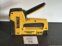 Side view of yellow and black DeWalt stapler with model number and branding visible.