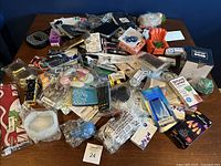 Wide view of the lot showing many small new household and personal items arranged on a table including textiles, stationery, and boxed personal care goods.