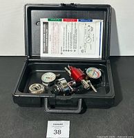 Open black carrying case showing vacuum venturi cooling system refiller components and instruction manual inside. Case clip broken.