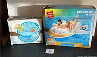 Photo showing two boxed pool floats: a Play Day Private Jet Float and a flamingo inflatable float