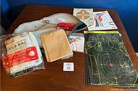 Overview of all lot items on a table, including deer bag, targets, hanging kit, and case.