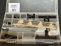 View of the plastic compartment box with tire patches, tire levers, and two T-handle tools inside.