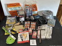 Full view of assorted tools and adhesives including power drill, foam weather stripping, adhesive tubes, bits, and small hardware items