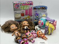 Assorted small dolls, miniature ponies, boxed BMe Make Your Own Lip Balm kit, Toy Mini Brands miniatures and other small collectible toys.