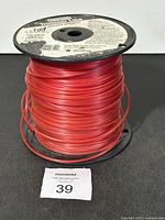 Full front view of the red trimmer line spool showing the label and line wound on the reel.