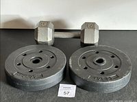 Photo showing two 10 lbs cast iron weight plates with multiple holes and one 25 lbs gray hex dumbbell.