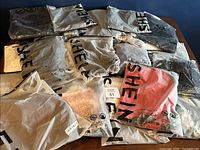 Overview of twelve clothing items packaged in translucent SHEIN plastic bags, showing variety in styles and colors, including soft hues and subtle patterns.