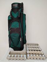 Green and black Bennington golf bag standing upright next to cartons holding golf balls.