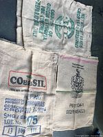 Top view of 4 burlap coffee sacks showing various printed markings including "COHOSIL", "ROYAL", AMSA" and other coffee producer information with lot numbers and country origins like Honduras and Brazil.