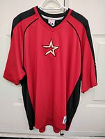 Front view of red and black Houston Astros baseball jersey with star logo on chest, hanging on white hanger.