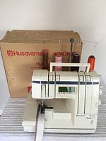 Front view of serger with box and five thread cones mounted