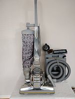 Full front view of upright vacuum, bag, power nozzle, hose and caddy with attachments visible