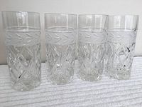 Four clear crystal highball glasses with an etched leaf band above the diamond cut pattern, shown side by side.