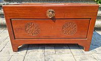 Front view of the rosewood blanket chest showing carved circular motifs and brass locking hardware.