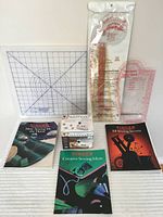 Photo showing three vintage Singer sewing books with colorful covers and quilting rulers, cutting mat, and bobbin winder in original box on white background.