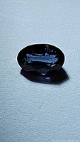 Close-up of flawless natural Ceylon blue sapphire gemstone, oval cut, deep blue color on a neutral background.