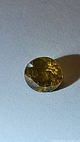 Photo of natural round cut African sphene gemstone showing the yellow-green facets and luster.