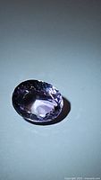 Close-up of oval cut natural amethyst gemstone showing facets and color under light