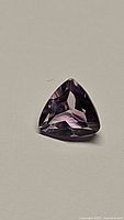 Close-up photo of a natural Brazilian amethyst gemstone, purple in color, with a trillion cut.
