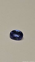 Top-down view of oval faceted tanzanite on neutral background