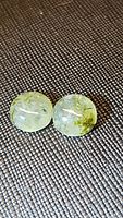 Pair of round natural moss agate cabochon gemstones on dark textured background showing translucency and green moss inclusions.