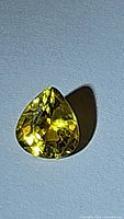Natural heart-shaped vivid canary yellow sapphire viewed from above, showing facet reflections and clarity under direct light.