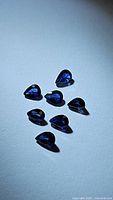 Seven natural pear-cut royal blue sapphire gemstones arranged on a plain surface.