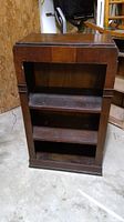 Front view of the vintage wooden bookshelf showing three open shelves and top surface.