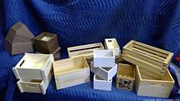 Overview photo of varied wooden crates, boxes and risers arranged showing different shapes, sizes and finishes including light unfinished wood, white painted and dark stained pieces.