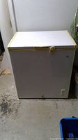 Full view of exterior front of white deep freezer with yellow trim and latch.