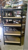 Front view of black metal garage shelf unit with five wood shelves in storage area.