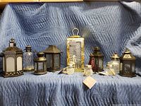 Full view of all lanterns and oil lamps laid out on padded blanket, showing size and variety.