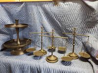 Photo showing three metal faux scale balances and the two-tiered metal serving tray against a blue padded backdrop.
