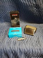 Image showing a cordless air inflator retail box, Amazon Echo Auto box, black car waste bin, and a small metallic box possibly a tire pressure gauge or accessory.