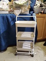 Photo of white metal wheeled 3-tiered cart with three trays